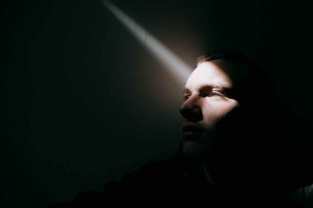 unemotional man in dark room in sunbeam
